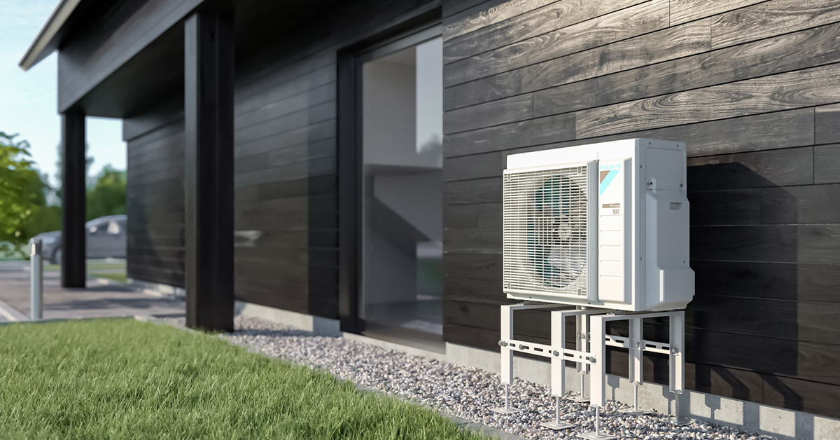 Ilma-vesilämpöpumpun ulkoyksikkö mustaa talon seinää vasten.