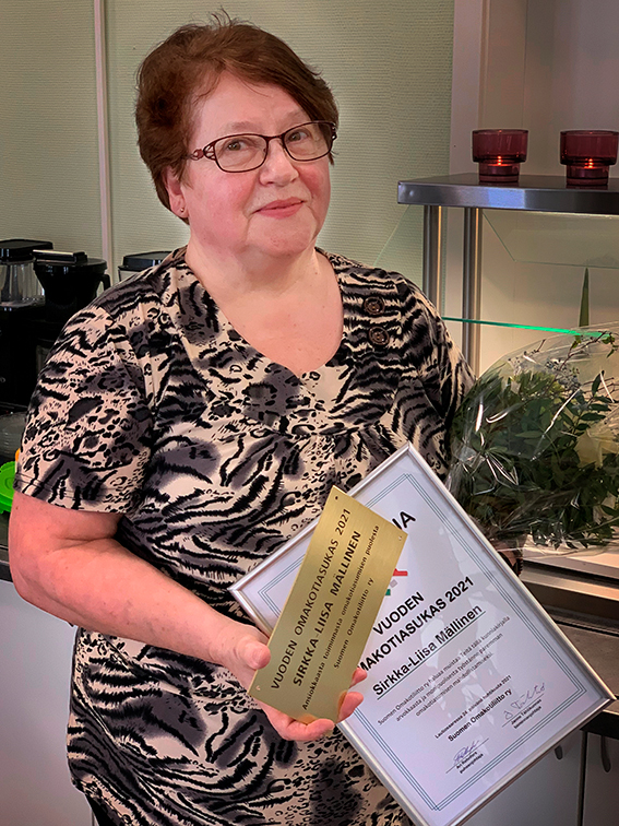 Kuvassa Sirkka-Liisa Mällinen pitelee Vuoden Omakotiasukas palkintoa