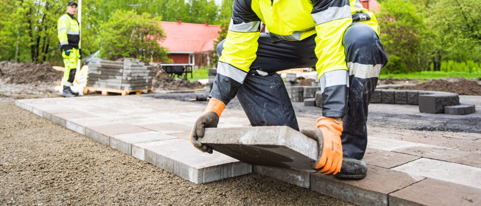 Asentaja asettaa pihalaattaa paikoilleen asennushiekan päälle.