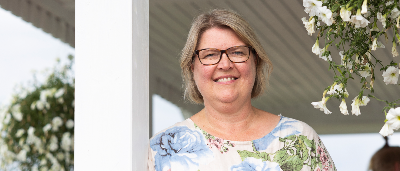 Omakotiliiton toiminnanjohtaja Marju Silander hymyilee pientalon kesäkukilla koristellulla terassilla