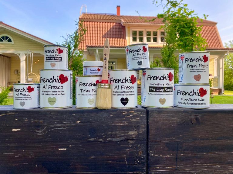 Frenchic-maalipurkkeja kivimuurin päällä, taustalla omakotitalo