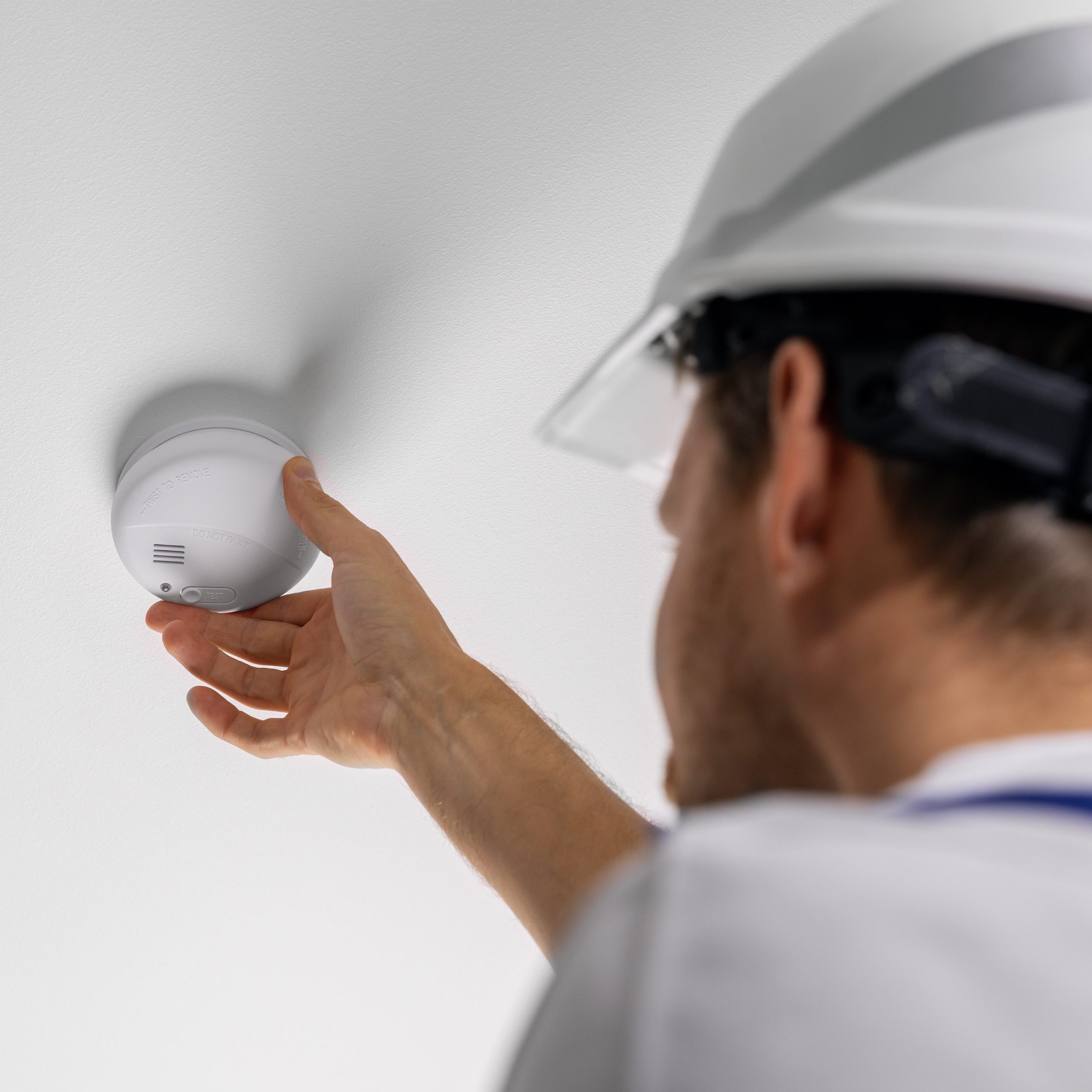 Asentaja asentaa palovaroitinta kattoon.