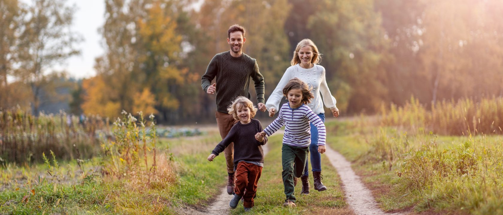 Äiti, isä ja kaksi lasta syksyisessä maastossa.