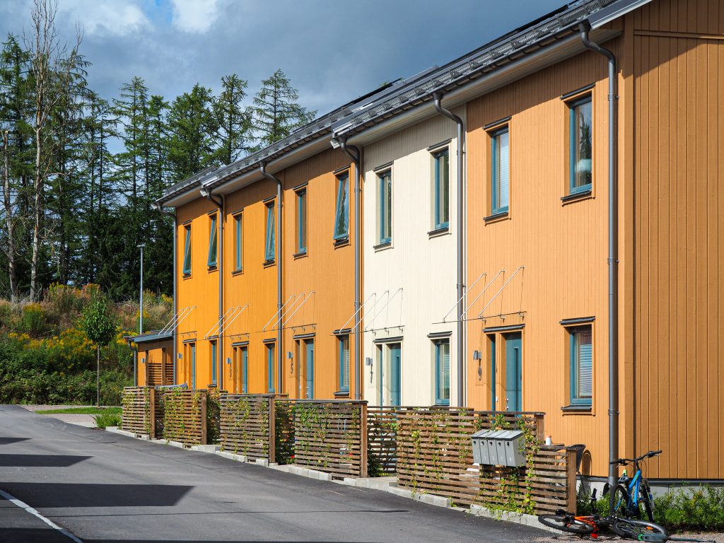 Rivitalo jossa kukin asunto on eri keltaisen sävyinen. Puissa on silmut.