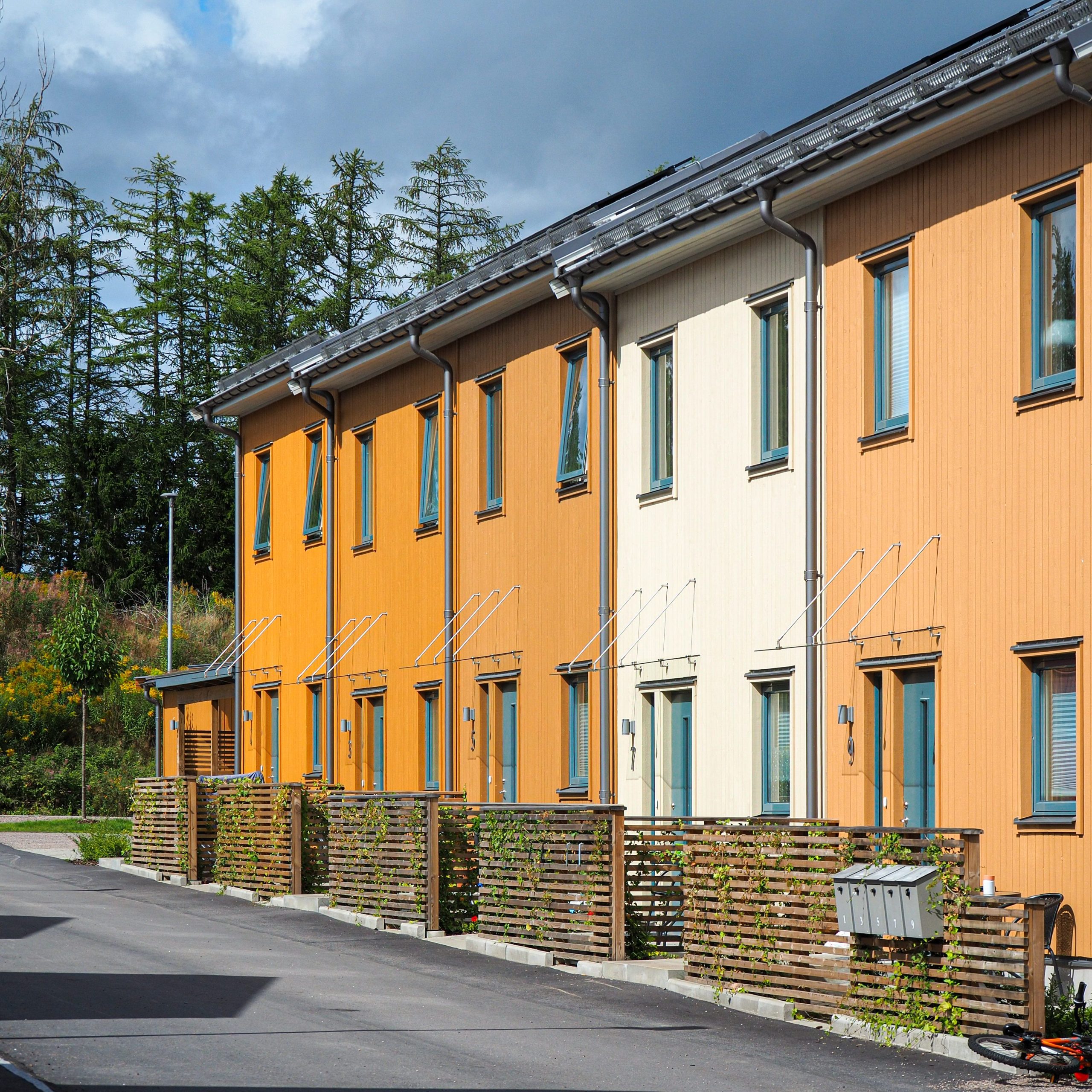 Rivitalo jossa kukin asunto on eri keltaisen sävyinen. Puissa on silmut.