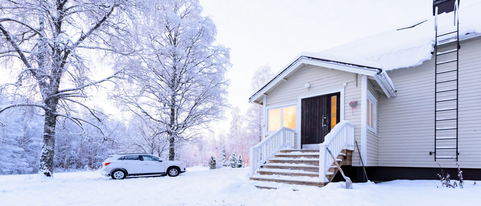 Vaalea puutalo lumisessa maisemassa