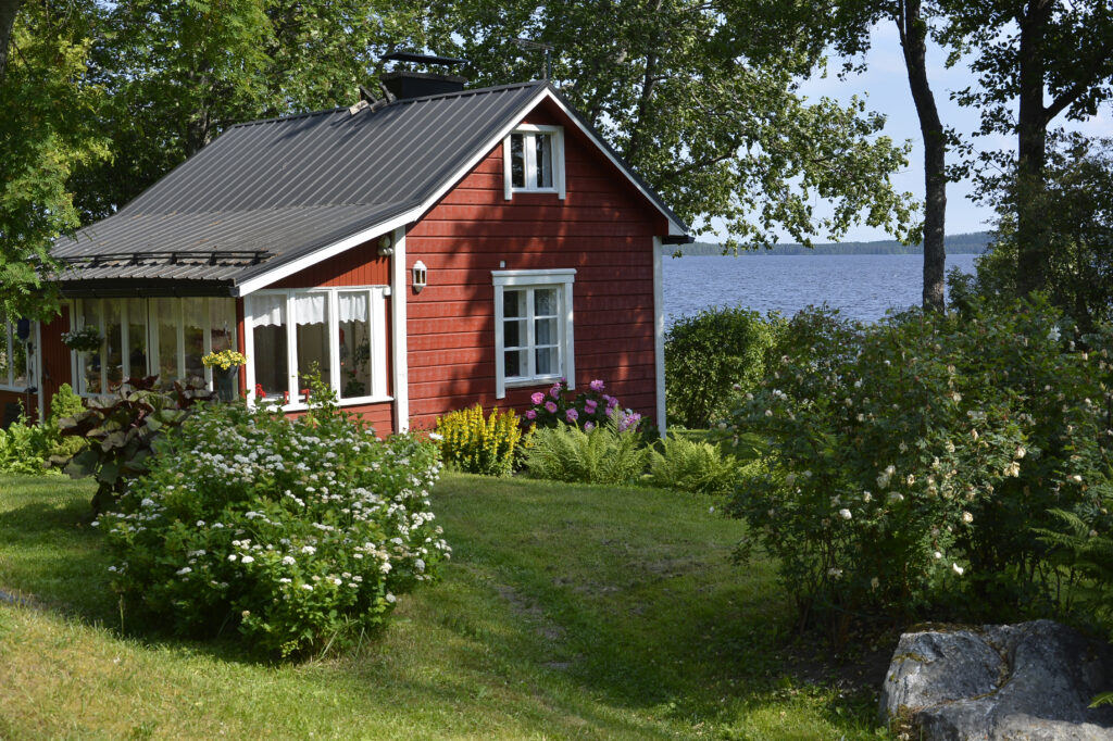 Pieni punainen mökki järven rannalla
